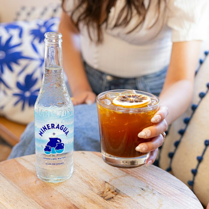 a woman sitting on a couch holding a glass of soda