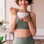 바쁜 직장인을 위한 건강관리, 작은 변화가 큰 차이를 만든다 a woman in a sports bra top holding a bowl of food