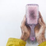 “요즘 머리가 너무 자주 빠져요”… 환절기 탈모는 어떻게 관리할까요? a person holding a hair brush in their hands