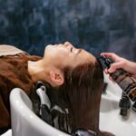 두피부터 모발까지, 2024년 헤어 건강 트렌드는 ‘맞춤형 케어’가 이끈다 a woman getting her hair washed in a sink