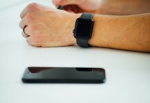 “직장인 건강, 스마트하게 챙기자: 웰니스 트렌드로 사무실이 바뀐다” black smartphone near person's hand wearing black smartwatch