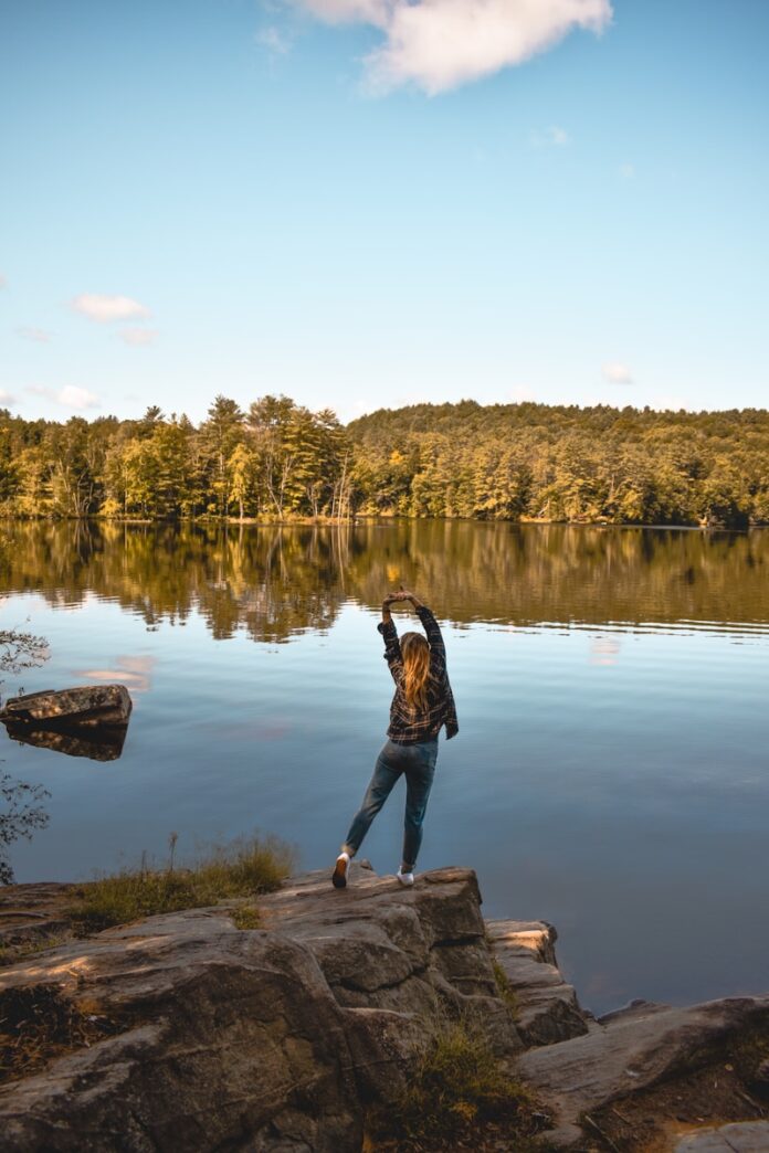 Photo by Ashlyn Ciara a woman standing on a rock near a body of water