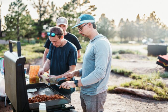 Photo by Land O'Lakes, Inc. Three men cooking food on an outdoor grill.