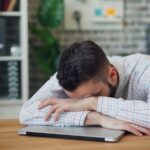 만성피로, ‘휴식 습관’이 해답… 일상에서 실천하는 에너지 회복법 a man sitting at a desk with his head in his hands