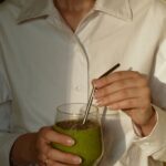 “웰니스 문화, 내 삶에 자연스럽게 녹아드는 건강 습관” person in white button up shirt holding clear drinking glass with green liquid