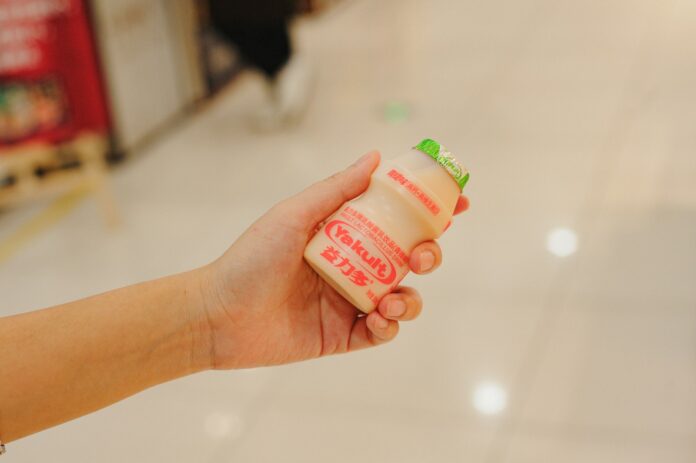 Photo by Joshua Fernandez Hand holding a bottle of yakult
